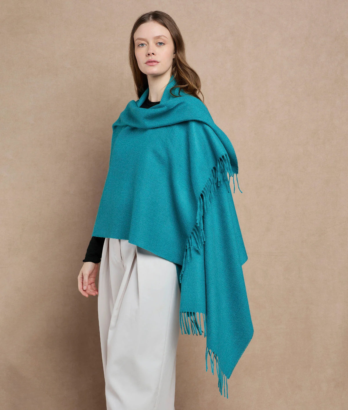 Woman wearing a teal blue-green fringed wrap.