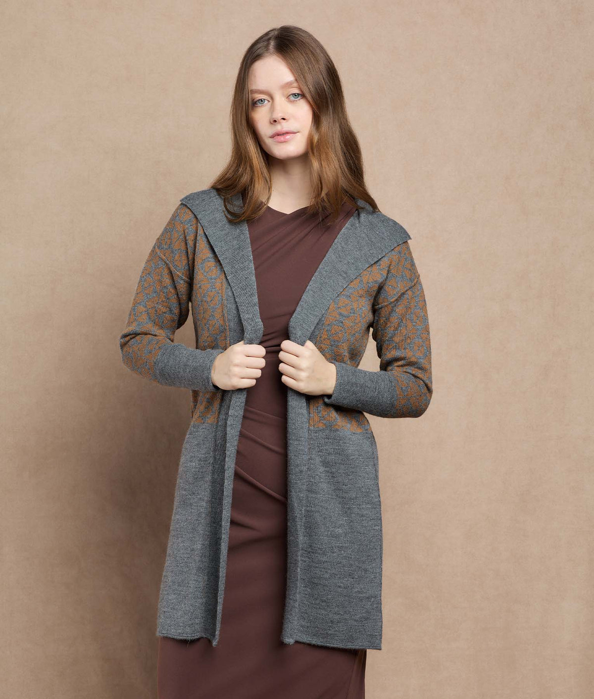 Woman wearing a long gray knit cardigan with orange geometric patterns.