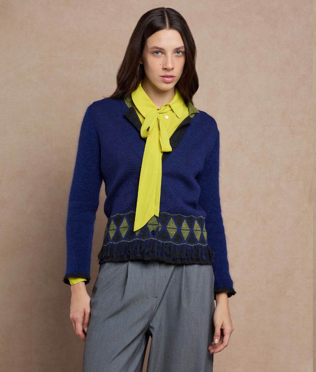 Woman wearing a navy blue knit cardigan with a geometric patterned hem.