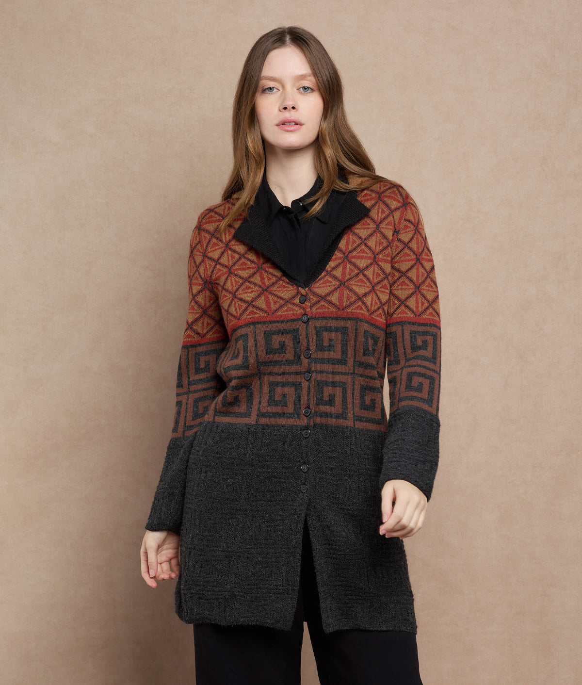 Woman wearing a button-front cardigan with rust-orange, brown and charcoal geometric patterns.