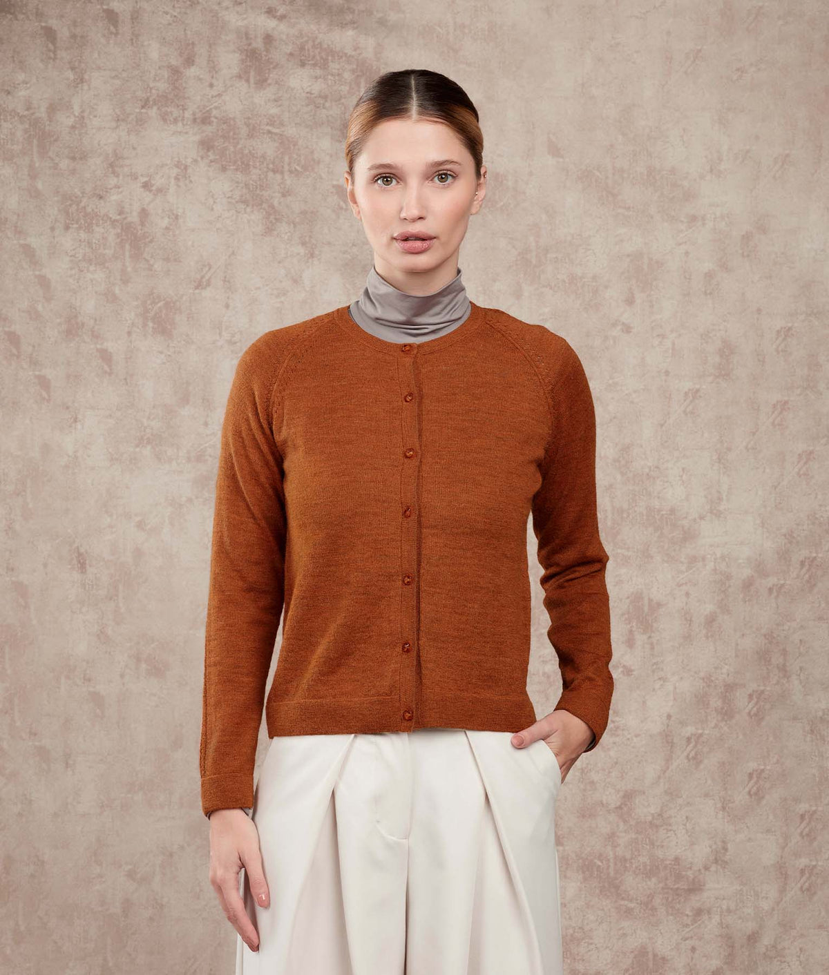 Woman wearing a rust-orange button-front cardigan.