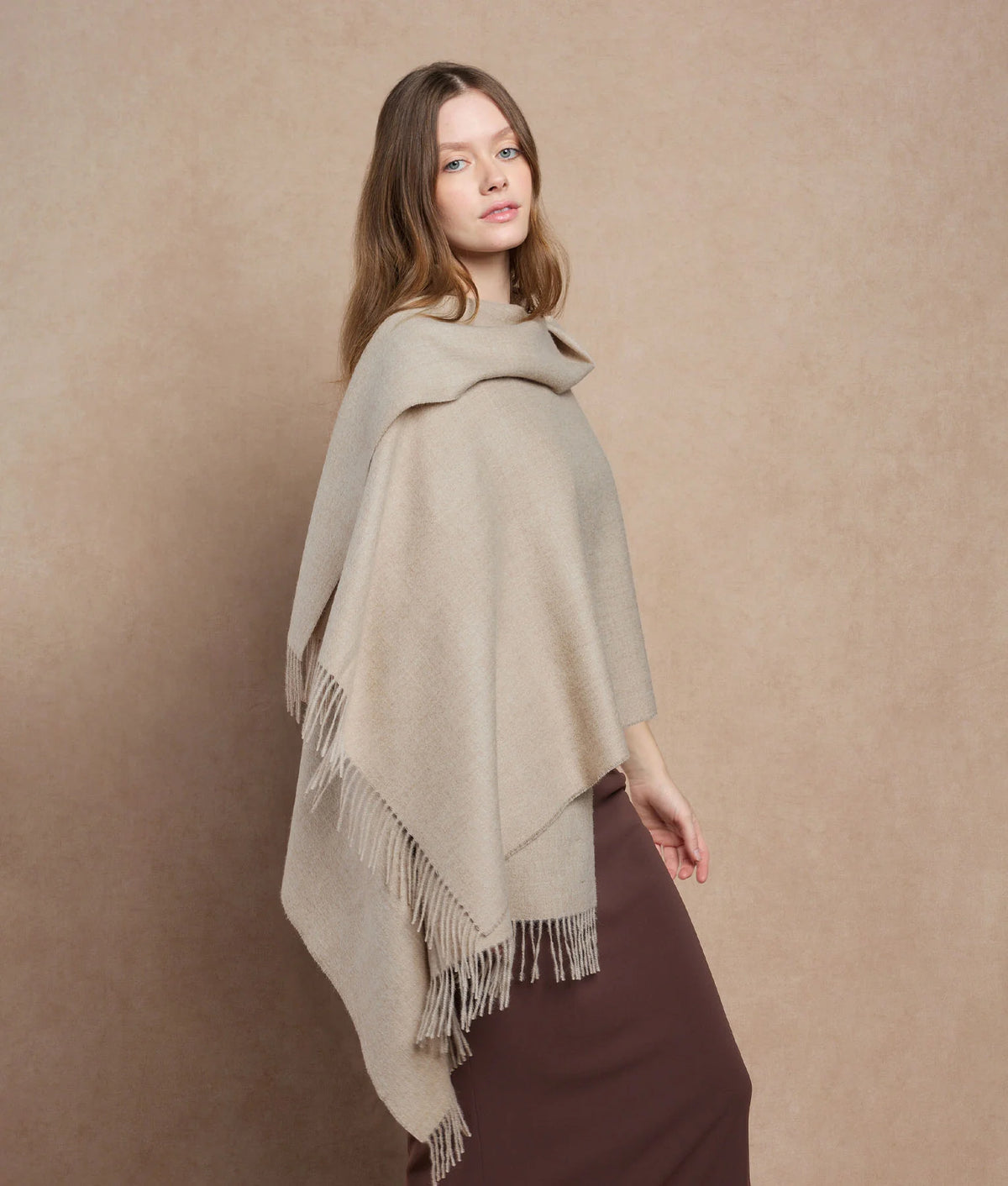 Woman wearing a beige fringed scarf.