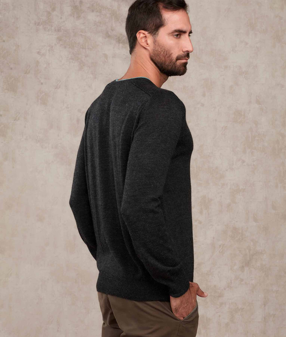 Side-back view of a man wearing a dark charcoal gray knit sweater.