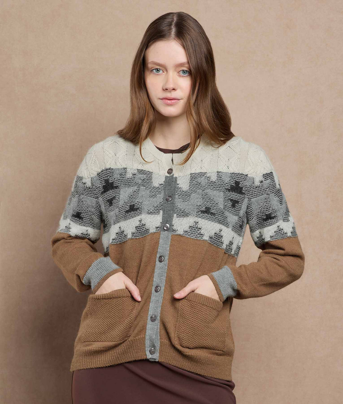 Woman wearing a color-block knit cardigan with a cream and gray geometric pattern and brown panels.