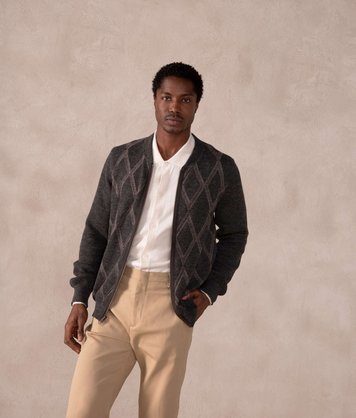 Man wearing a dark gray argyle knit cardigan.