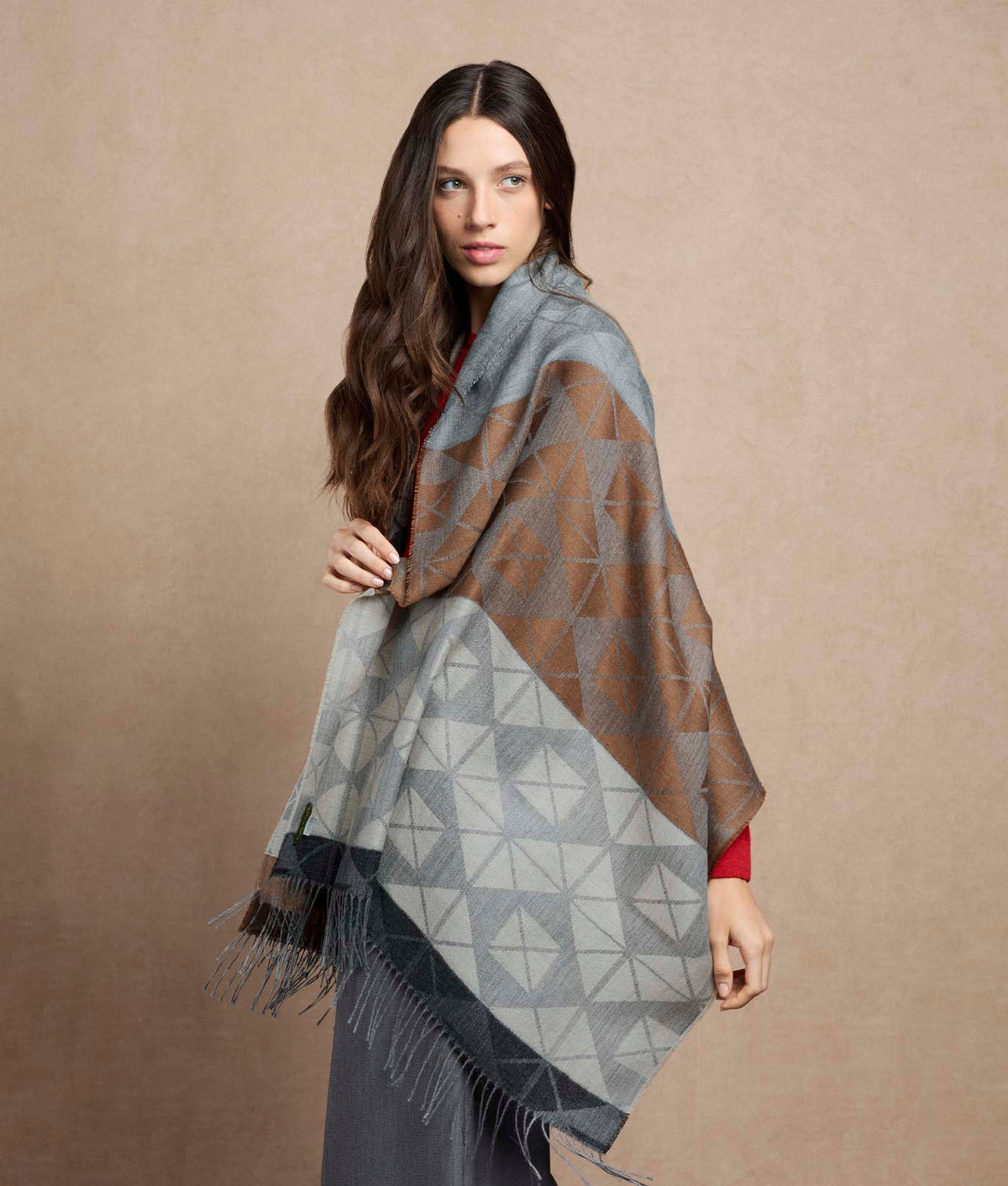 Woman wearing a large geometric patterned shawl in brown, gray and white.