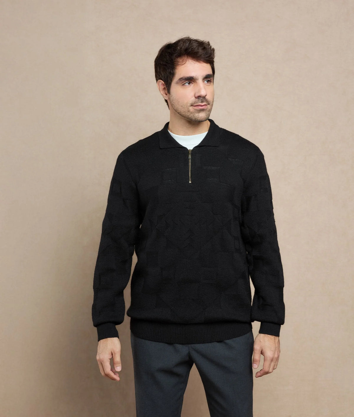 Man wearing a black quarter-zip knit sweater with a subtle geometric pattern.