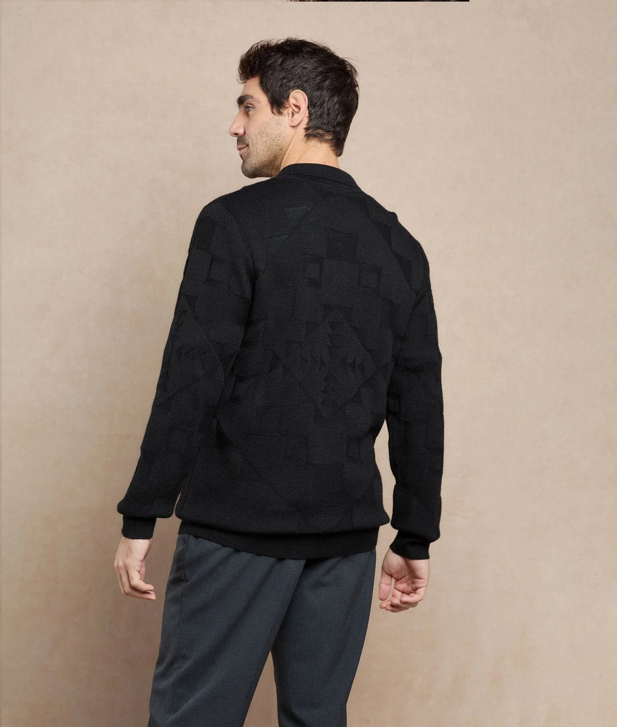 Back view of a man wearing a black textured knit sweater with a geometric pattern.
