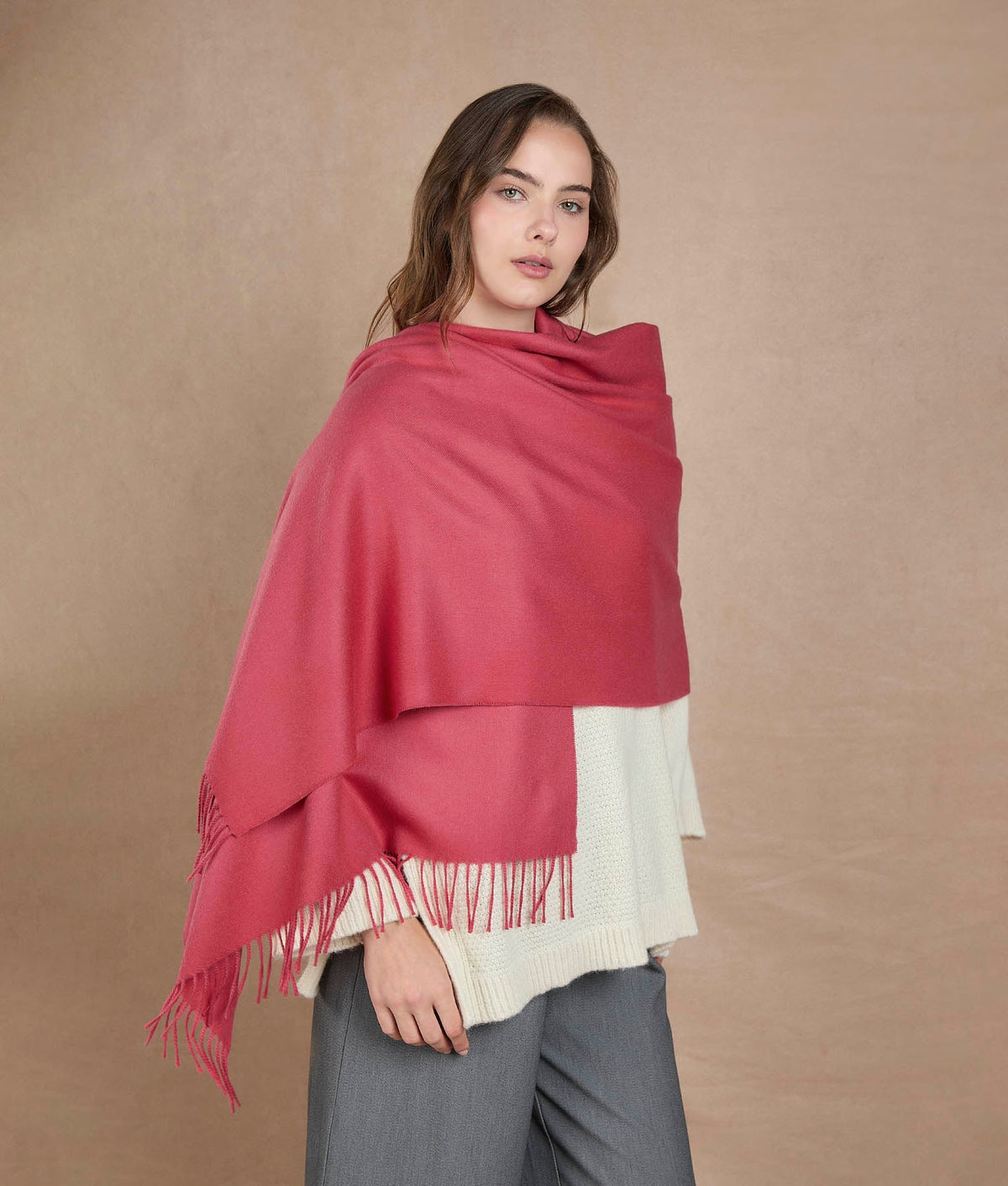 Woman wearing a dusty rose pink shawl with fringe trim.