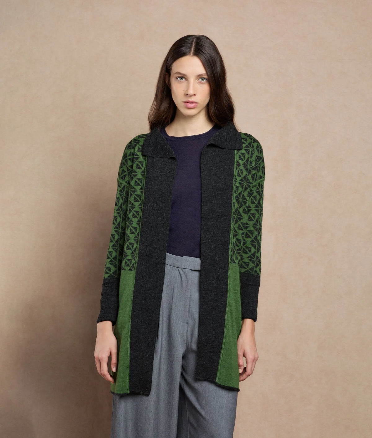 Woman wearing a long cardigan with dark green and black panels.
