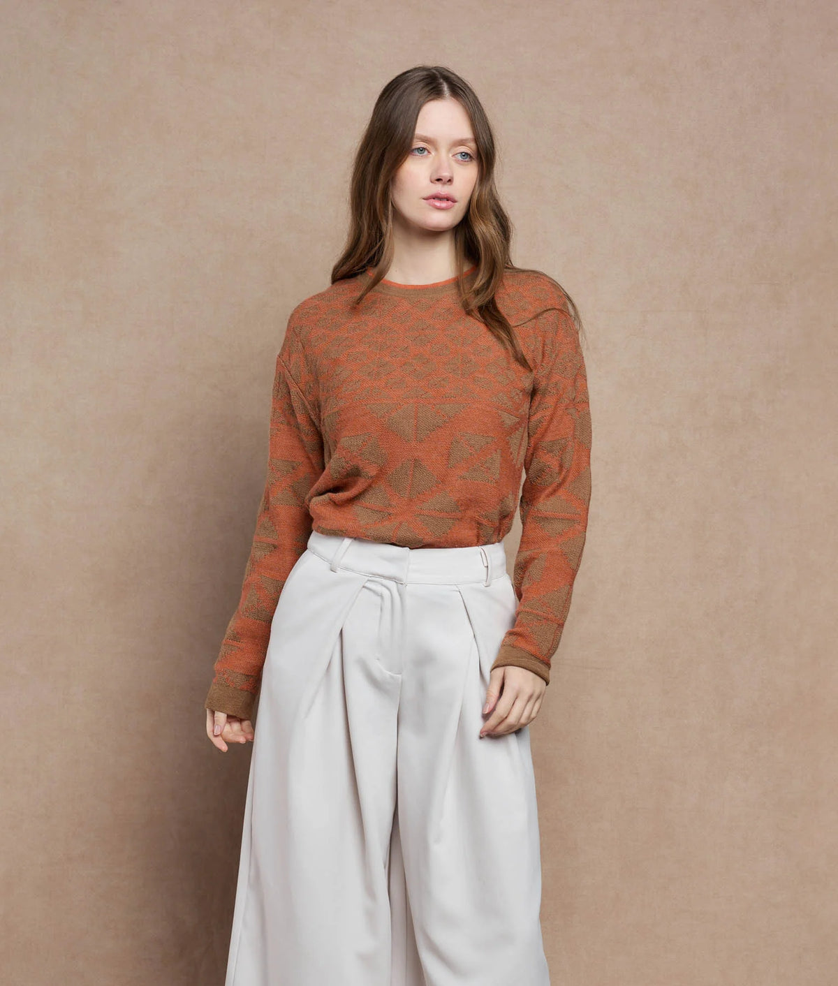 Woman wearing a rust-orange and brown patterned knit sweater.