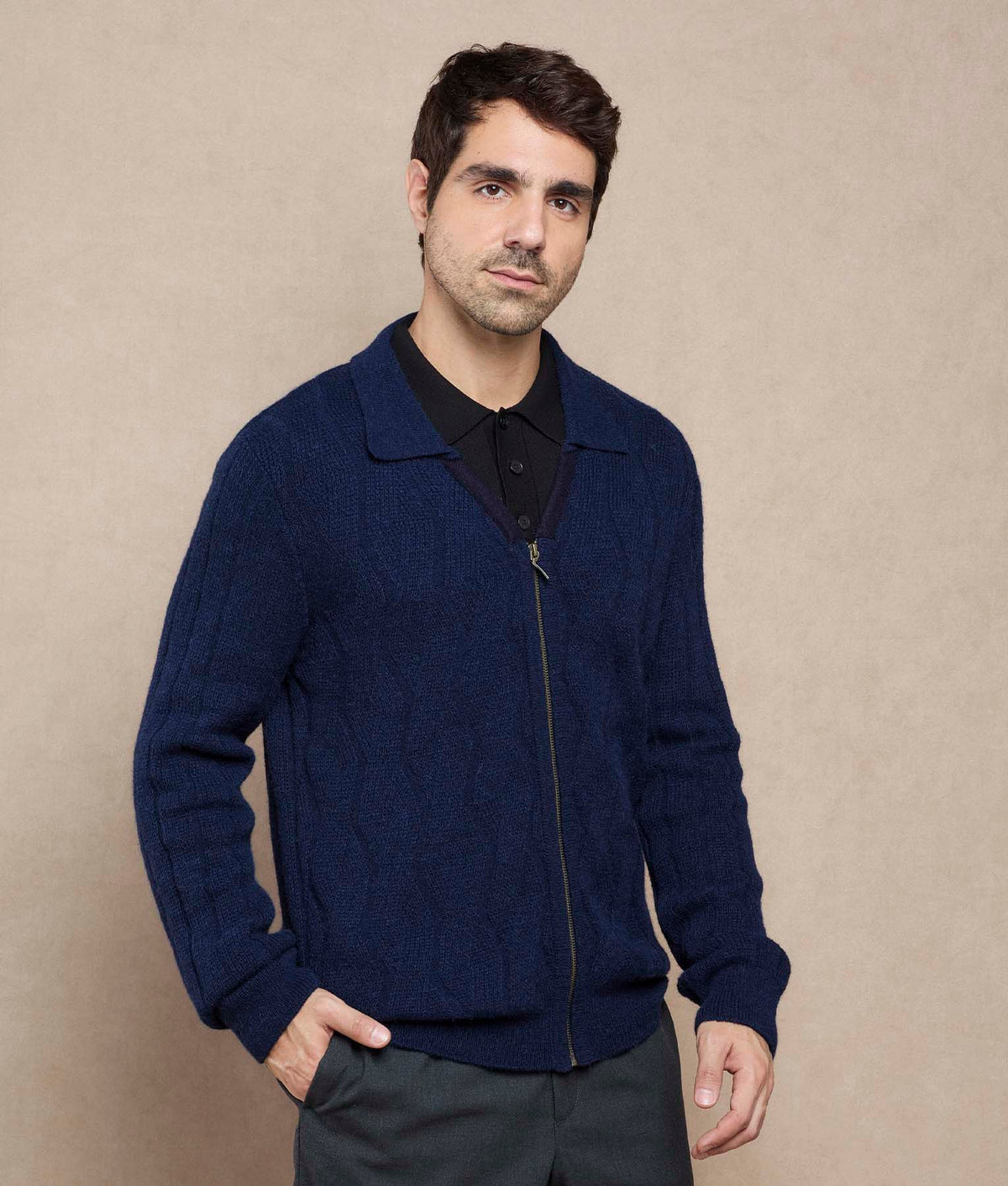 Man wearing a navy blue textured zip-up sweater.